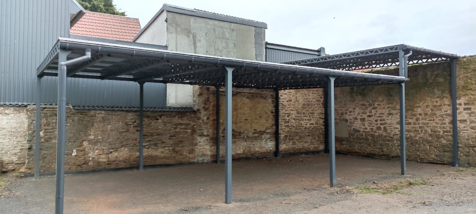 Carport-Anlage aus Stahl an einer Natursteinmauer