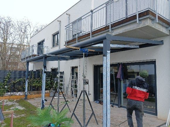 Monteure beim Aufbau einer Terrassenüberdachung an einem Reihenhaus